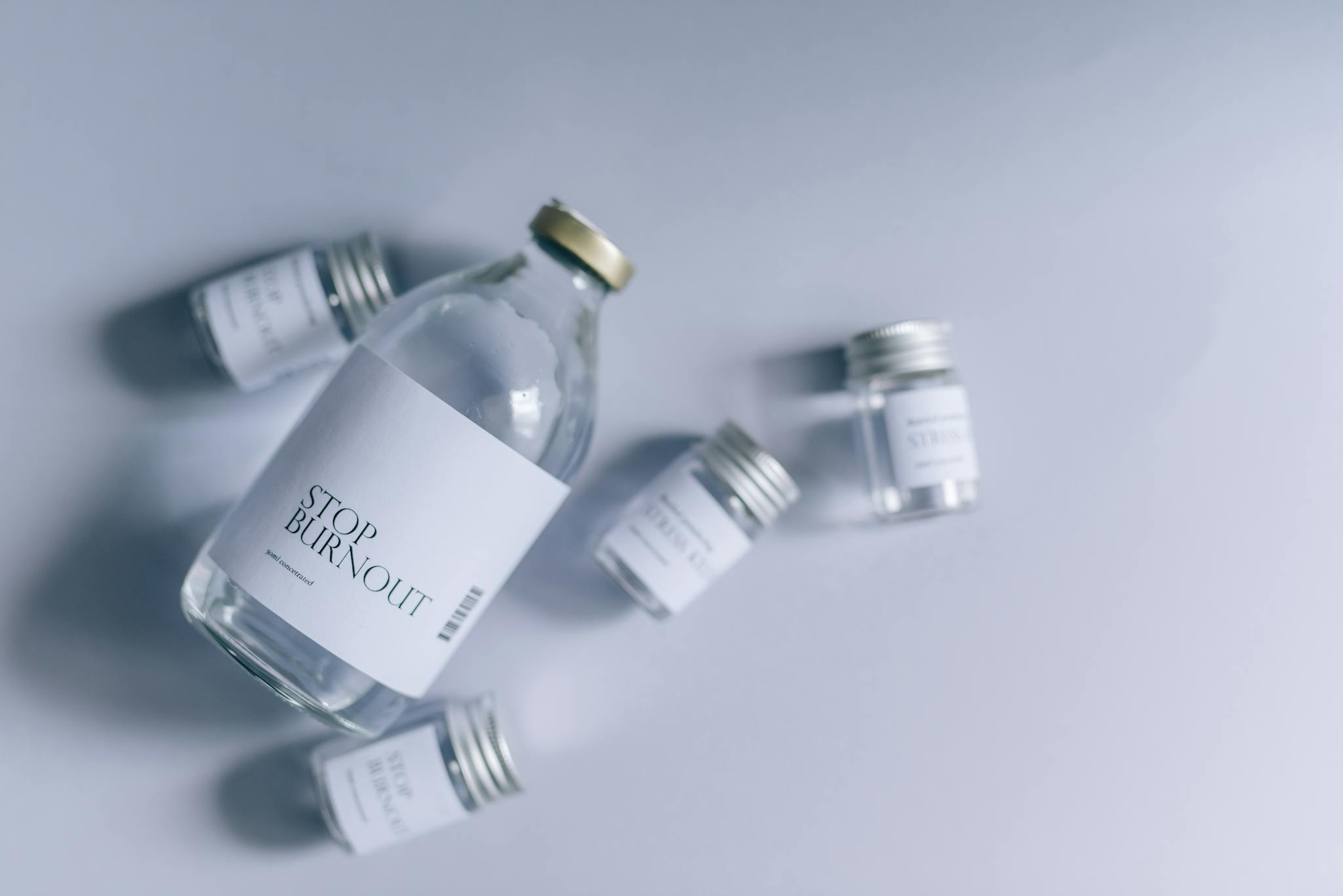 Glass bottles labeled 'Stop Burnout' arranged on a white background for a clean, healthcare-inspired image.